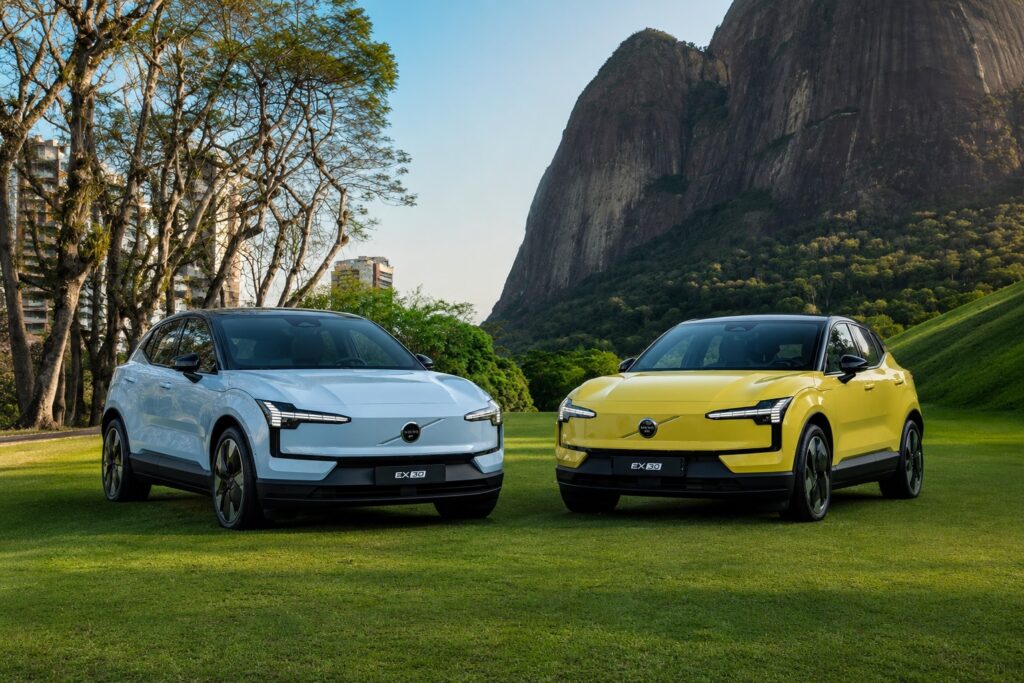 Dois Volvo EX30 elétricos nas cores azul-claro e amarelo em área verde