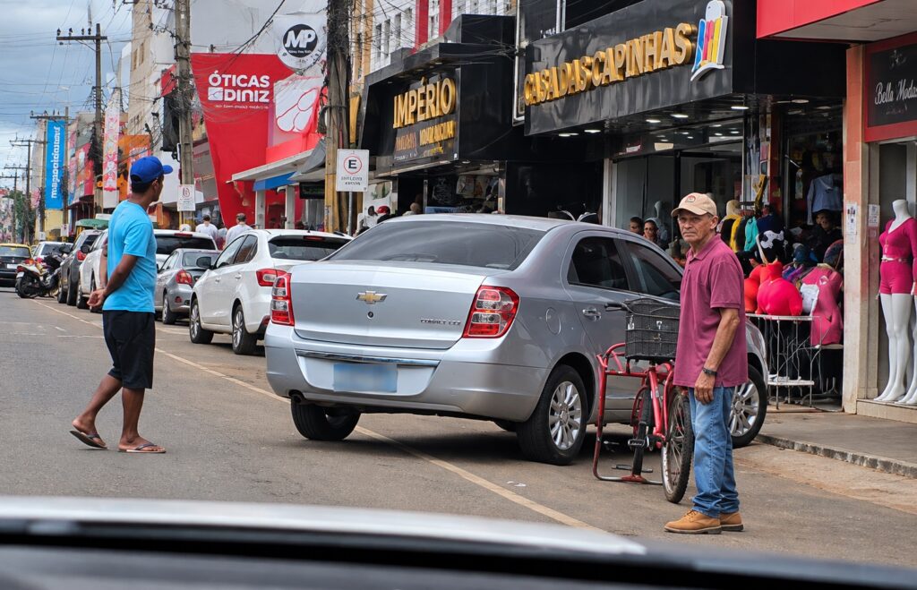 Carro estacionado parcialmente sobre a calçada em via urbana